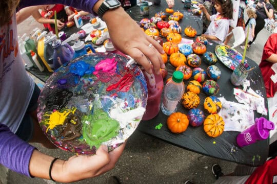 Alpharetta, GA, USA - September 30, 2017:  A woman squirts oil paint onto a palette to paint miniature pumpkins at the Scarecrow Harvest fall festival on September 30, 2017 in Alpharetta, GA.